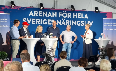 Personer på en scen deltar i en paneldiskussion med en skylt i bakgrunden som lyder Arenan för hela Sveriges näringsliv.